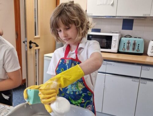 primary school boy washing dishes for a school event which is part of school life in england